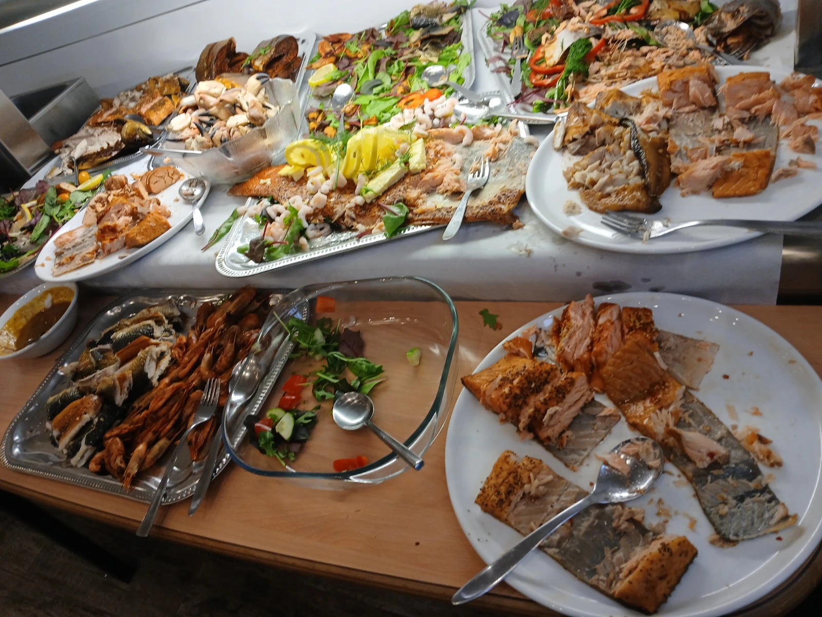 Franken Food Express – Catering für Partys – Dies scheint ein großes Meeresfrüchtebuffet mit verschiedenen Gerichten mit gekochtem Fisch, Garnelen und Beilagensalaten zu sein.