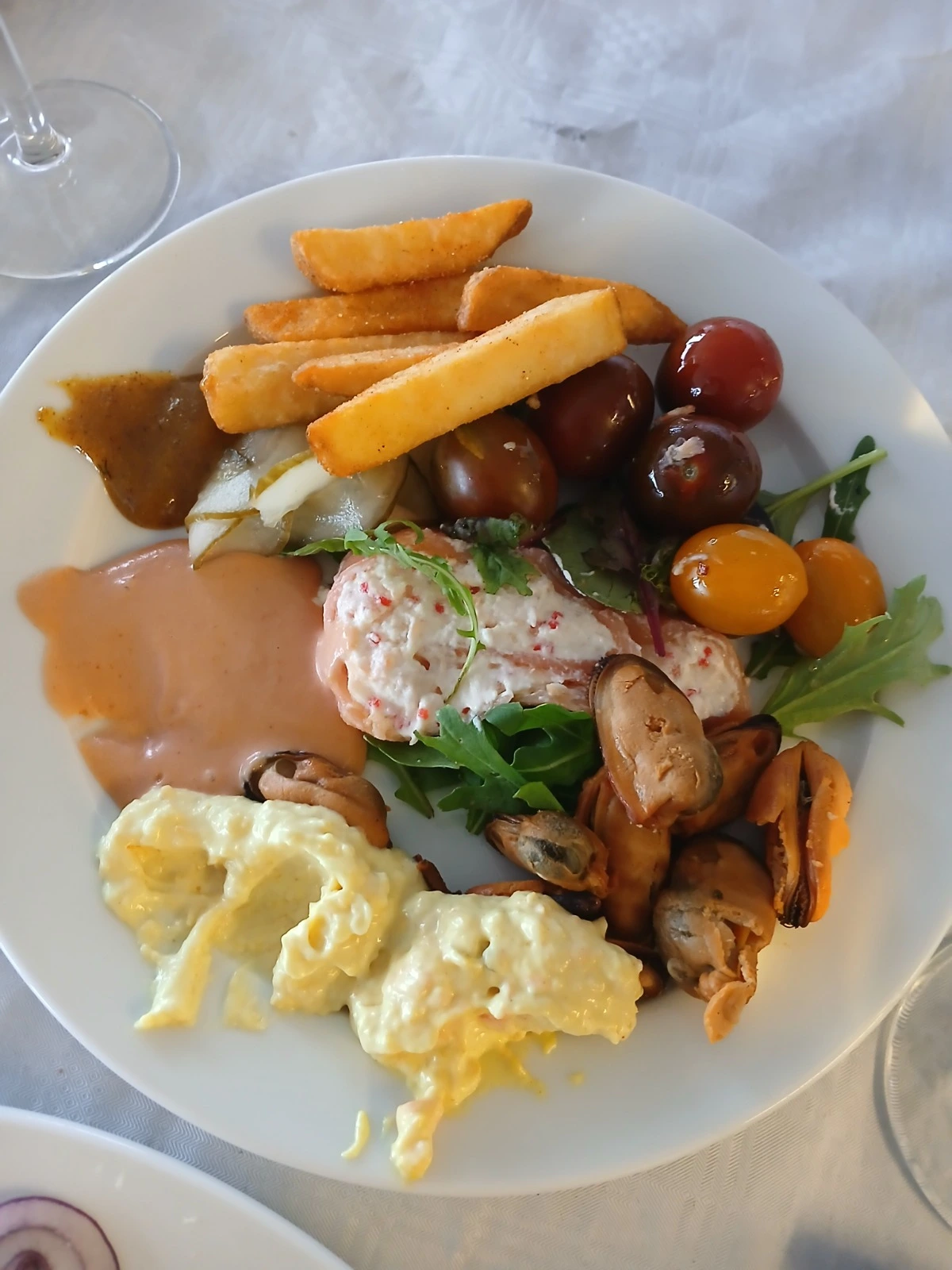 Franken Food Express – Partybewirtung – Dieser Teller enthält eine Mischung aus verschiedenen Speisen, vermutlich von einem Fischbuffet oder einer gemischten Vorspeisenplatte, darunter frittierte Muscheln und verschiedene Saucen.